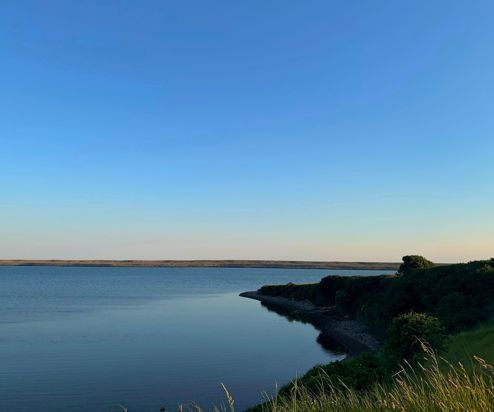 Fleet Lagoon at sunset with calm blue water and Chesil Beach in the background
