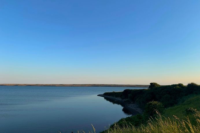 Fleet Lagoon at sunset with calm blue water and Chesil Beach in the background