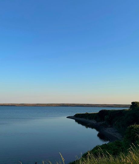 Fleet Lagoon at sunset with calm blue water and Chesil Beach in the background