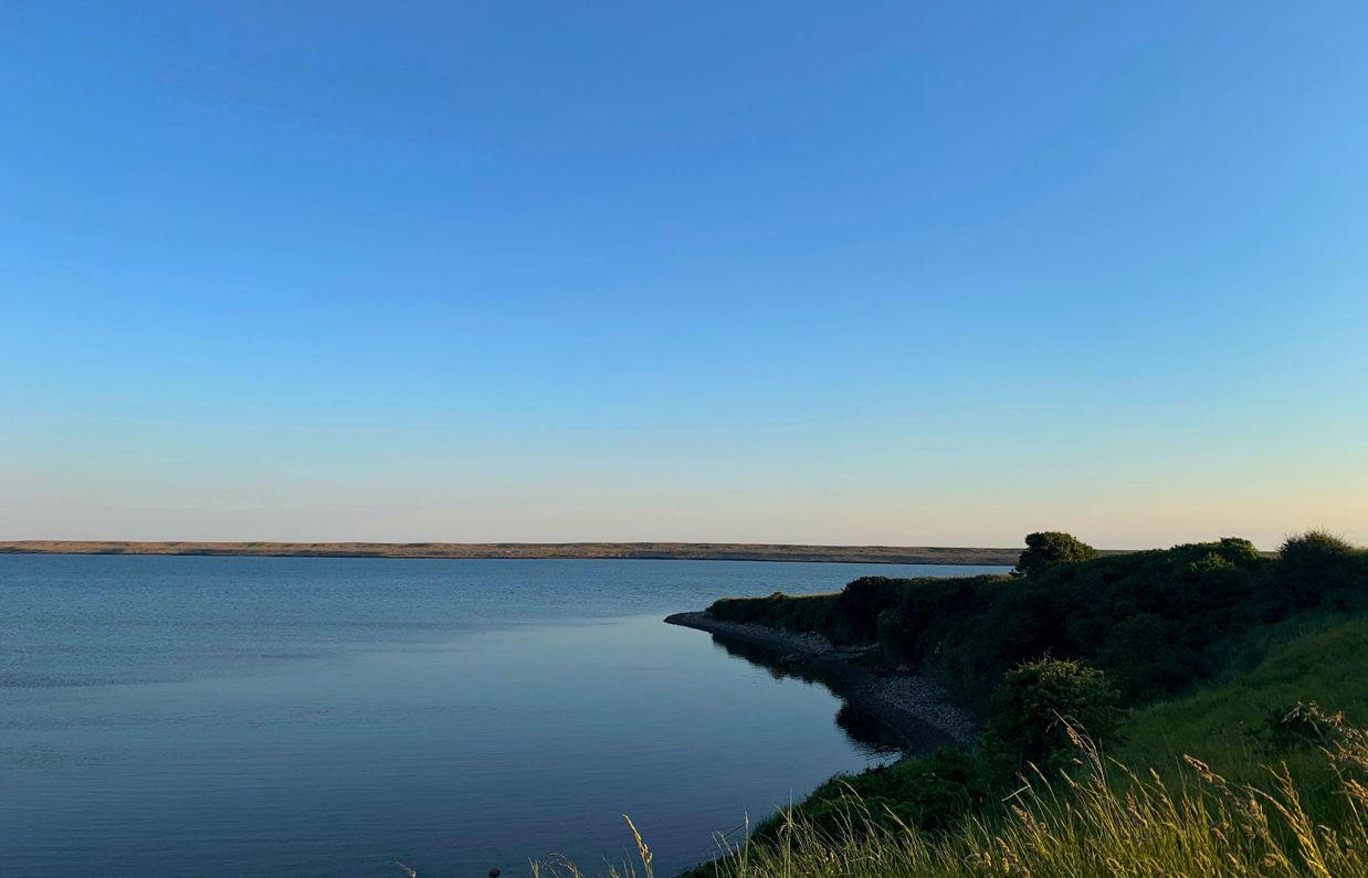 Fleet Lagoon at sunset with calm blue water and Chesil Beach in the background
