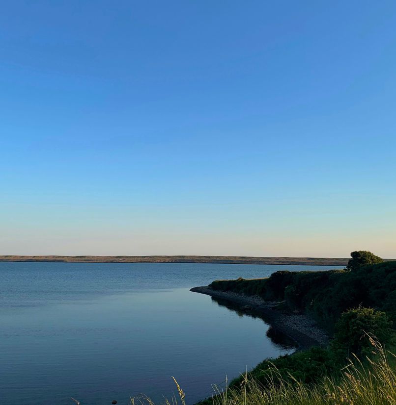 Fleet Lagoon at sunset with calm blue water and Chesil Beach in the background