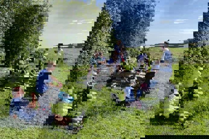 A group of people in the countryside sat taking a break on a walk