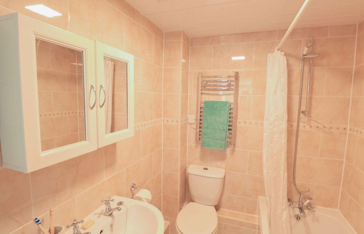 Internal of a cottage bathroom with shower over bath, toilet and sink