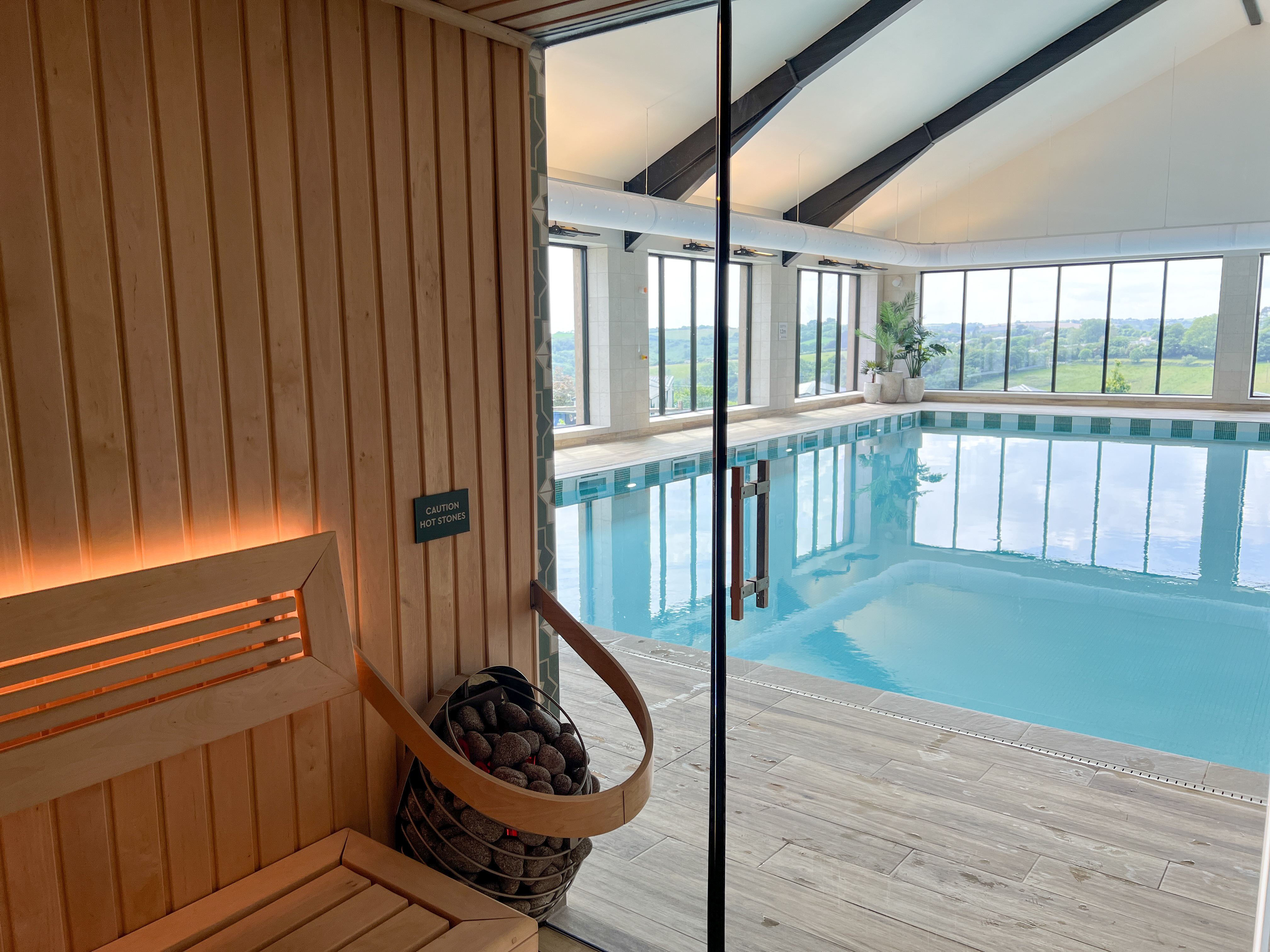 An indoor heated swimming pool and sauna within a barn style building with boho-chic styling and countryside views