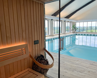 An indoor heated swimming pool and sauna within a barn style building with boho-chic styling and countryside views