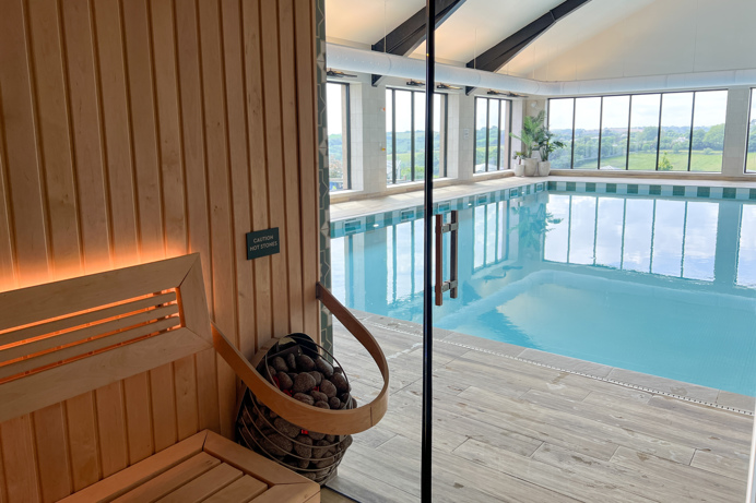 An indoor heated swimming pool and sauna within a barn style building with boho-chic styling and countryside views