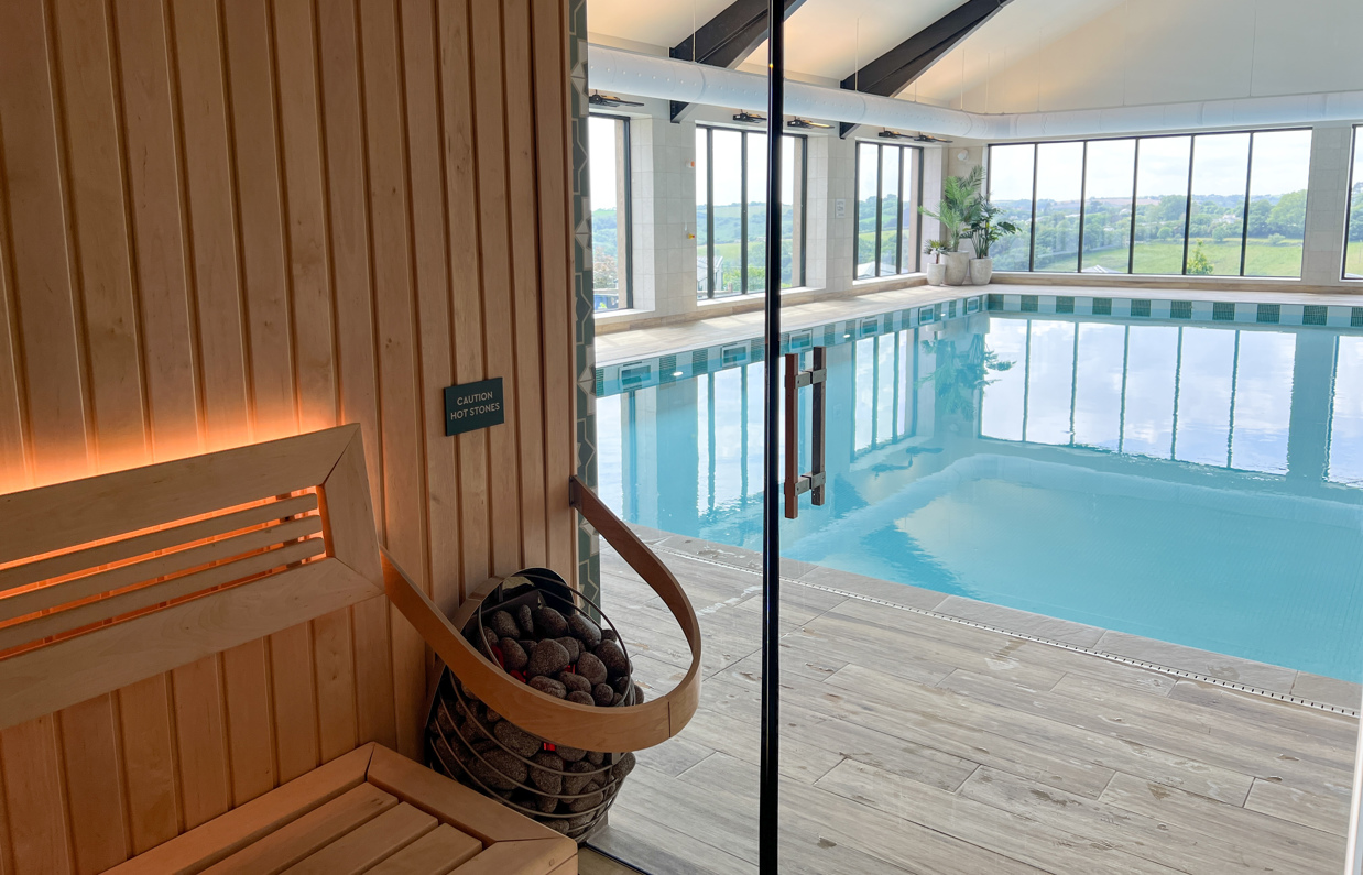 An indoor heated swimming pool and sauna within a barn style building with boho-chic styling and countryside views