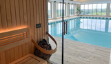 An indoor heated swimming pool and sauna within a barn style building with boho-chic styling and countryside views