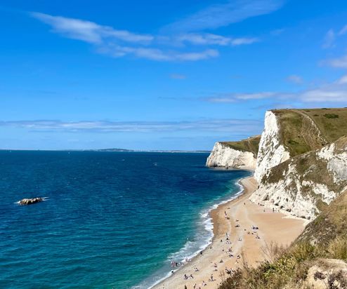 The view of Durdle Door Beach and beyond on a striking sunny, blue sky day with blue water