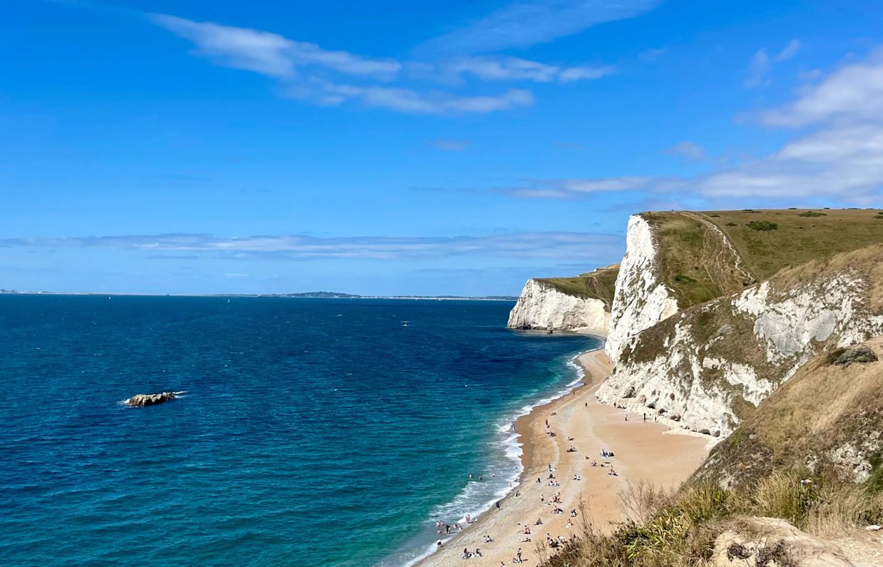 The view of Durdle Door Beach and beyond on a striking sunny, blue sky day with blue water