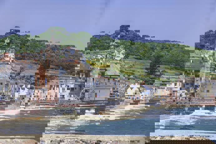 A small village on the coast with rolling countryside hills in the background