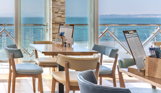 An up close shot of seating in Drift Bar & Grill with views of the sea and Weymouth Bay on a sunny, blue sky day