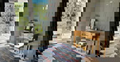 View out of master bedroom window onto decking with hot tub and trees beyond