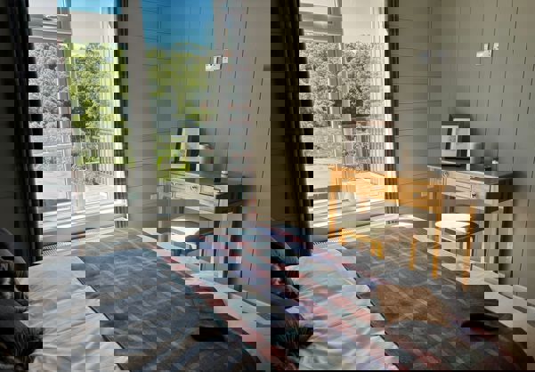 View out of master bedroom window onto decking with hot tub and trees beyond