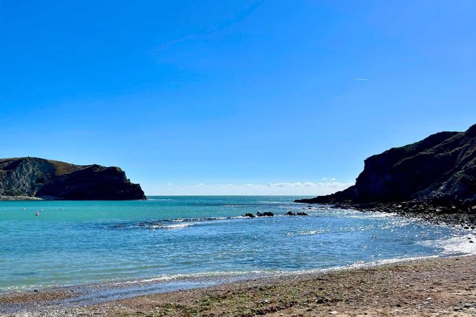 The view from Lulworth Cove out to sea on a striking sunny, blue sky day with blue water