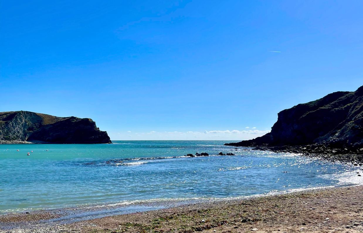 The view from Lulworth Cove out to sea on a striking sunny, blue sky day with blue water