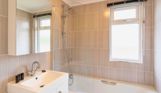 Internal of a lodge bathroom with shower over bath and sink