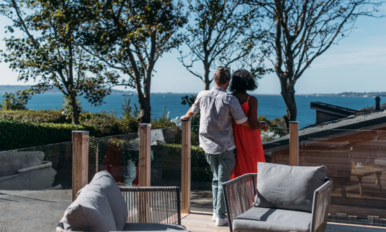 A couple cuddle and admire the view out to the sea and Portland from their decking
