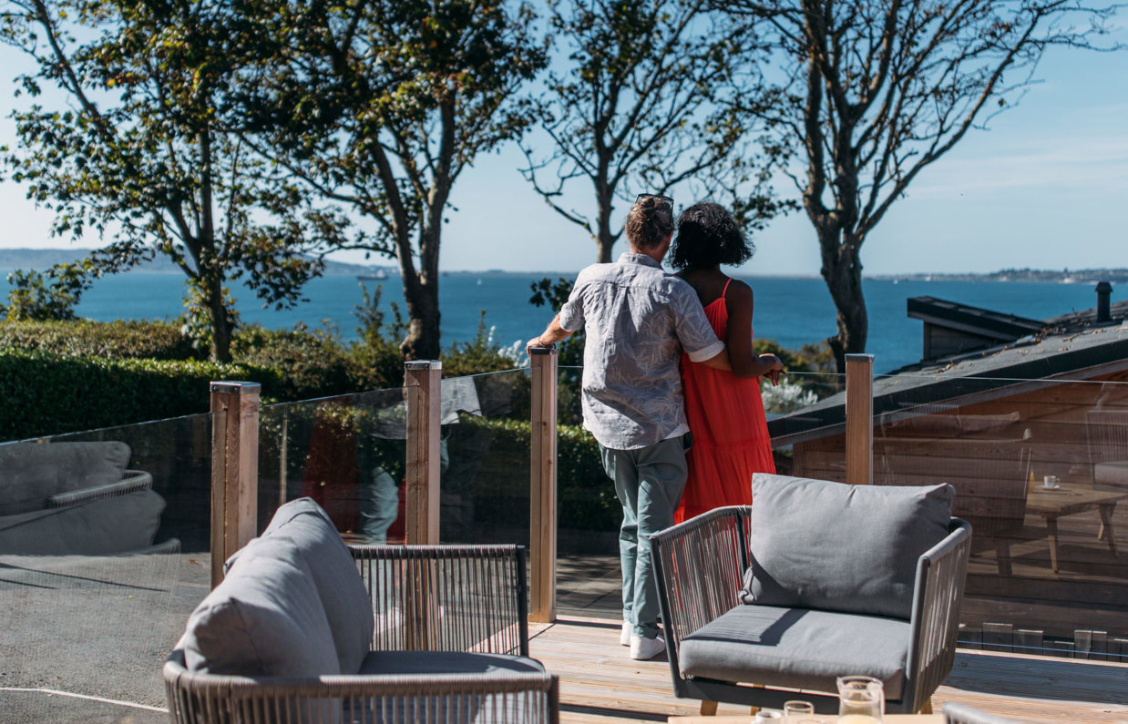 A couple cuddle and admire the view out to the sea and Portland from their decking
