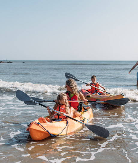 A family of four in the water by the coast kayaking