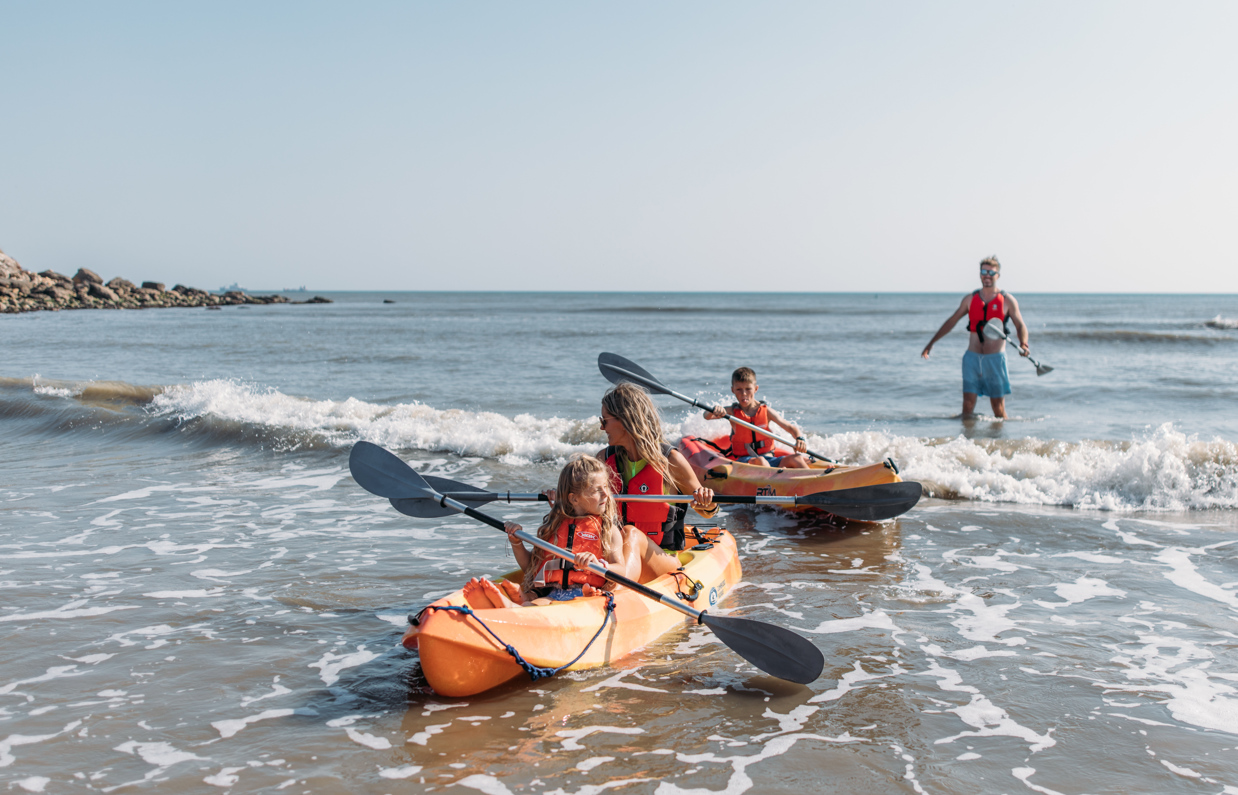 A family of four in the water by the coast kayaking