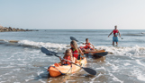 A family of four in the water by the coast kayaking