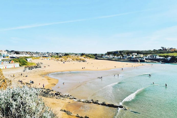 A sandy stretch of beach surrounded by a small town and beach huts