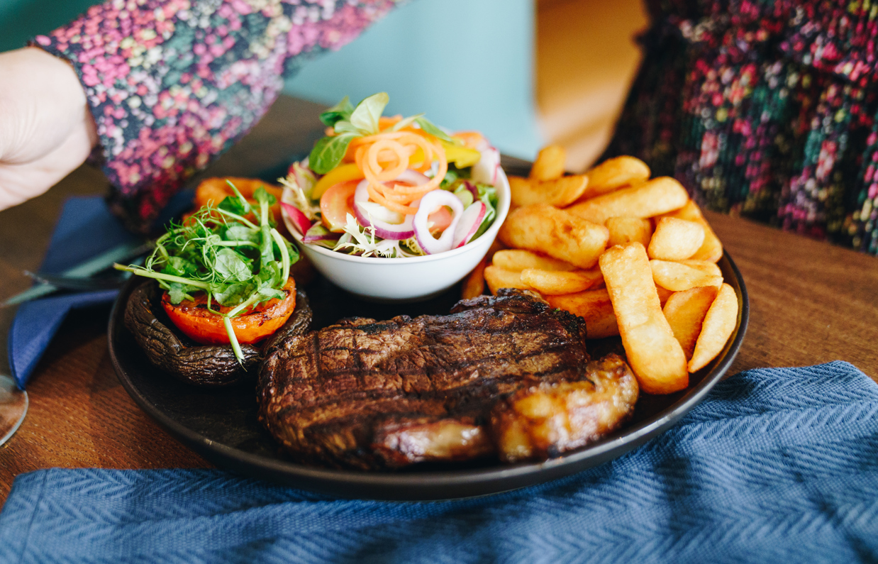 A steak and chips dish with salad