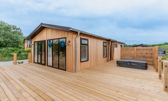 External of a luxury lodge on pitch with decking and hot tub
