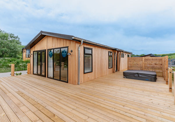 External of a luxury lodge on pitch with decking and hot tub