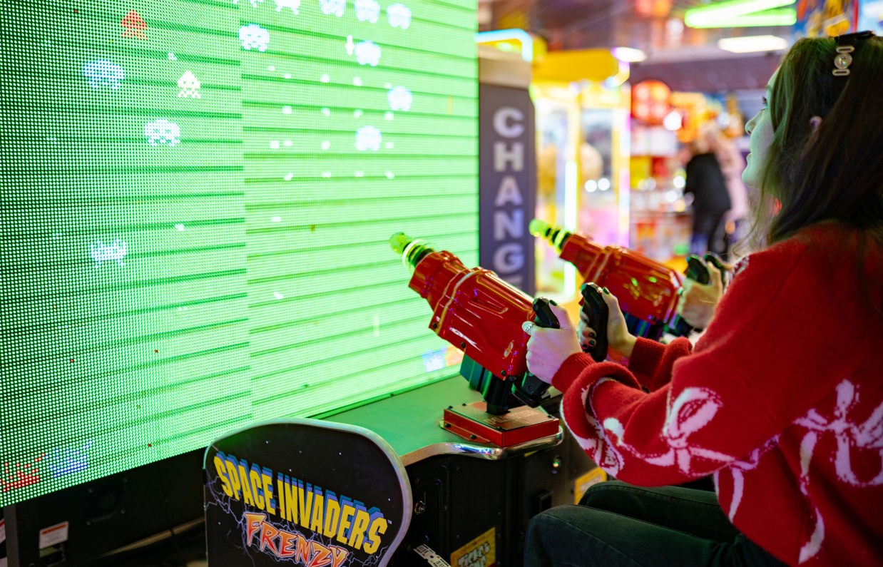 A girl playing space invaders game looking up at the screen
