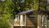 A holiday lodge with decking, surrounded by woodland