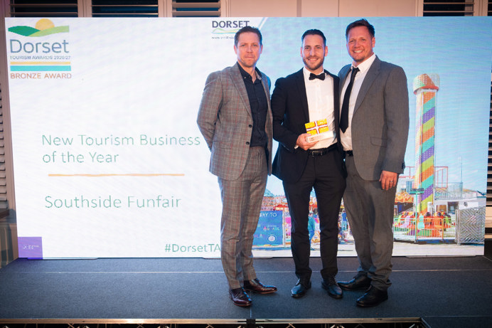 Three people standing smiling with an award