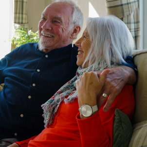 A couple sat laughing together on a sofa