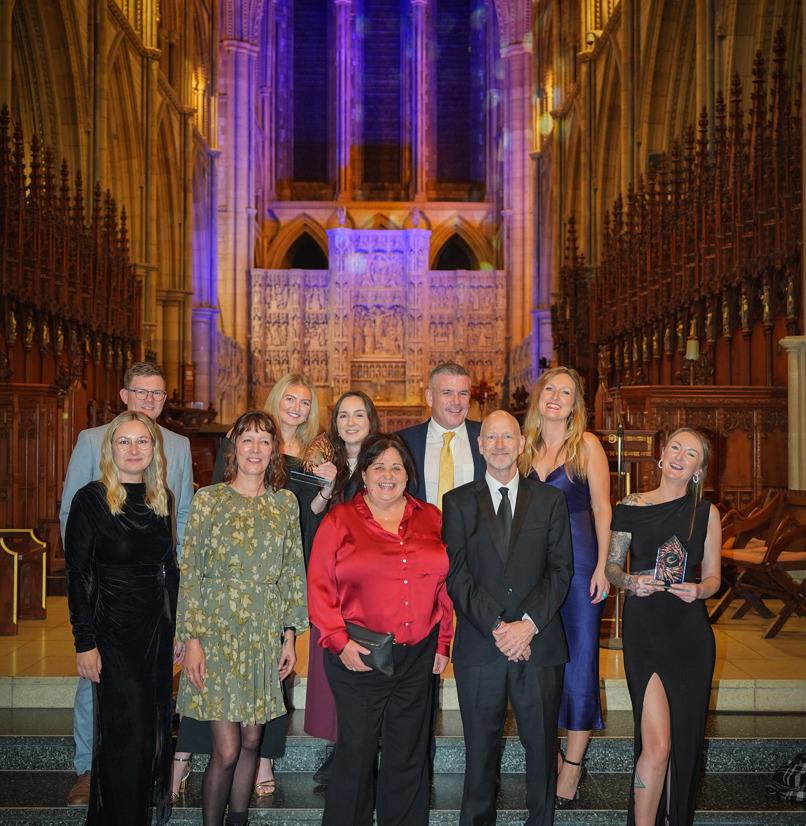 A group of people stood on steps within a cathedral with a dramatic backdrop
