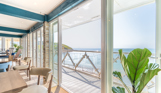 Views out to sea and coast from Drift Bar & Grill's seating area through wide open french doors on a sunny, blue sky day