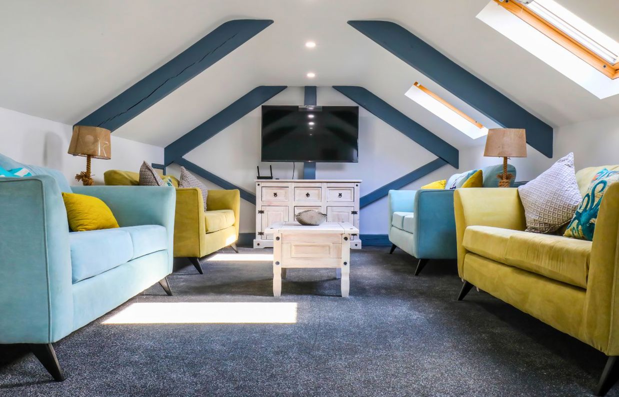 Internal of a cottage lounge with four sofas and a wall-mounted tv