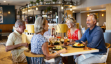 Two women and two men sat at a table in Breeze Bar & Grill smiling with plates of food