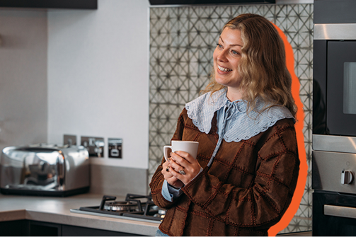 A lady smiling in a kitchen of a holiday home holding a mug