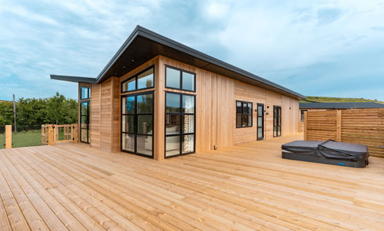 External of a luxury lodge on pitch with extensive decking and hot tub