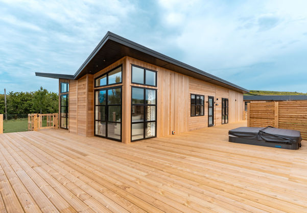 External of a luxury lodge on pitch with extensive decking and hot tub