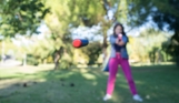 A female aiming a nerf gun with a nerf pellet flying towards the camera