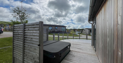 External of a luxury lodge on pitch with hot tub and decking