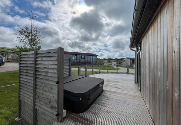 External of a luxury lodge on pitch with hot tub and decking