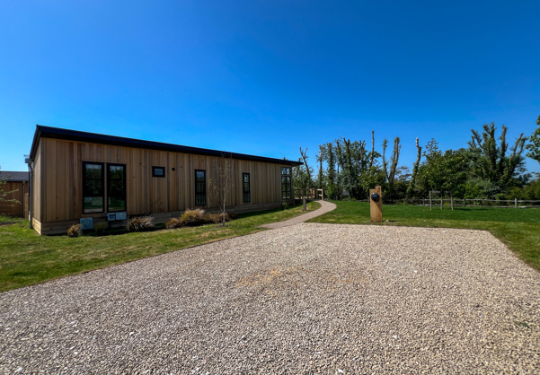 External of a luxury lodge on pitch with designated parking EV charging and green space