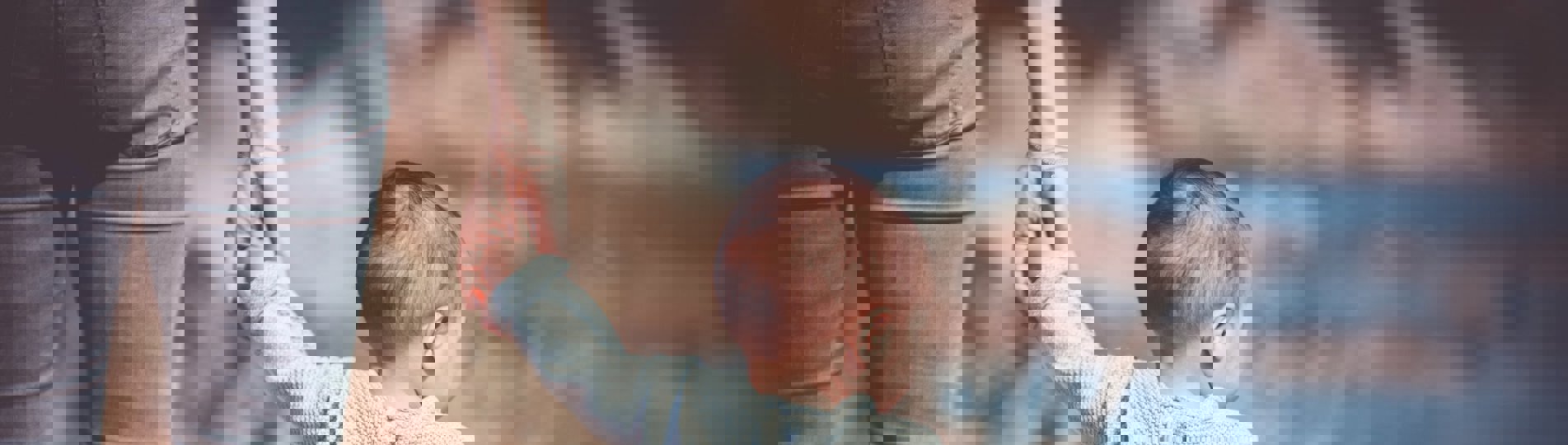 A young toddler walking along with coast holding an adult's hand