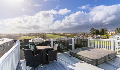 External of a caravan on pitch with decking, outdoor furniture, hot tub and countryside views