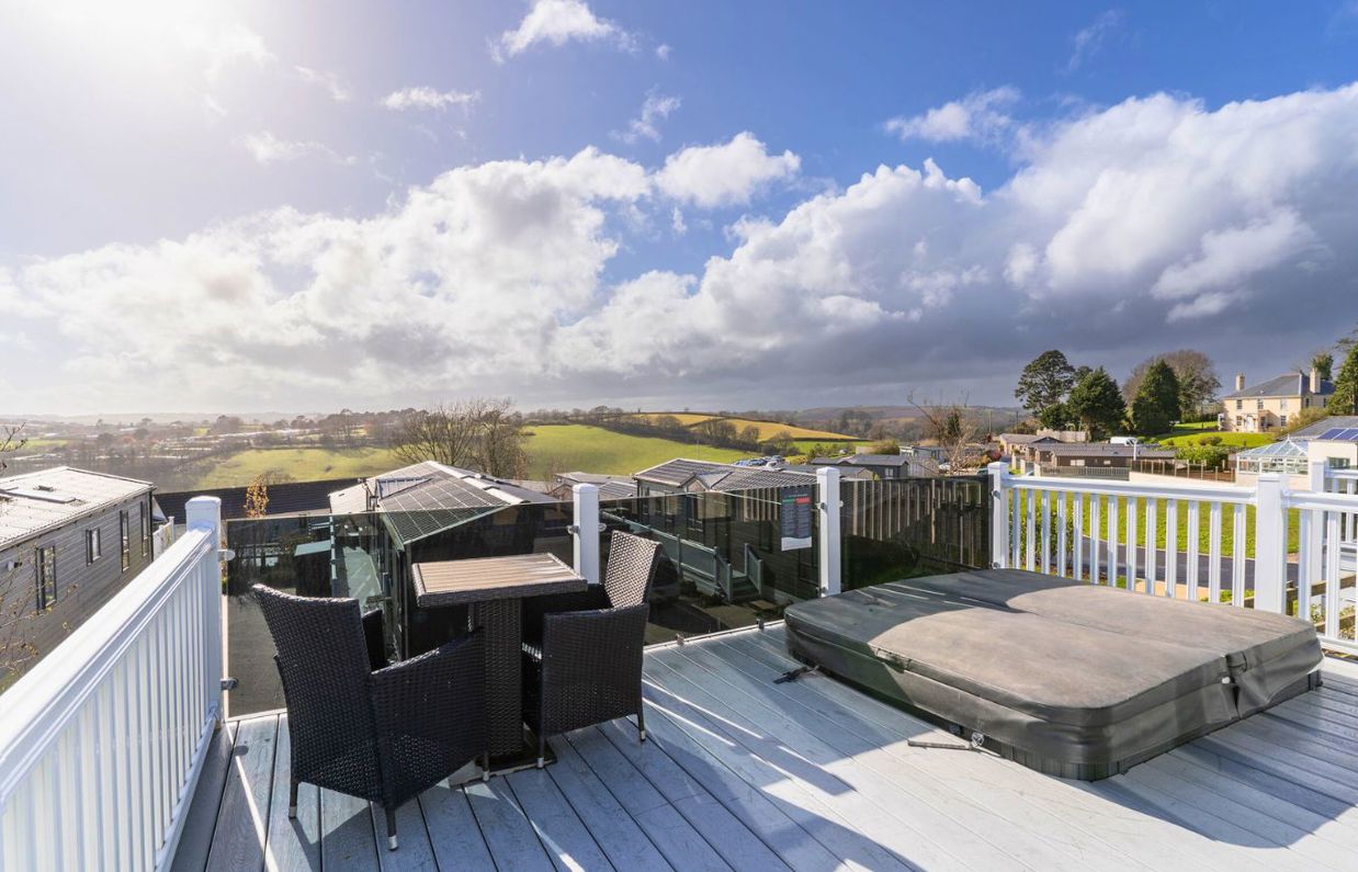 External of a caravan on pitch with decking, outdoor furniture, hot tub and countryside views