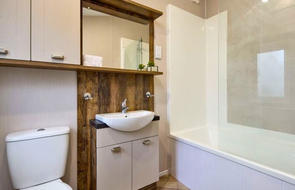 Internal of a caravan bathroom wit shower over bath, sink and toilet