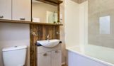 Internal of a caravan bathroom wit shower over bath, sink and toilet